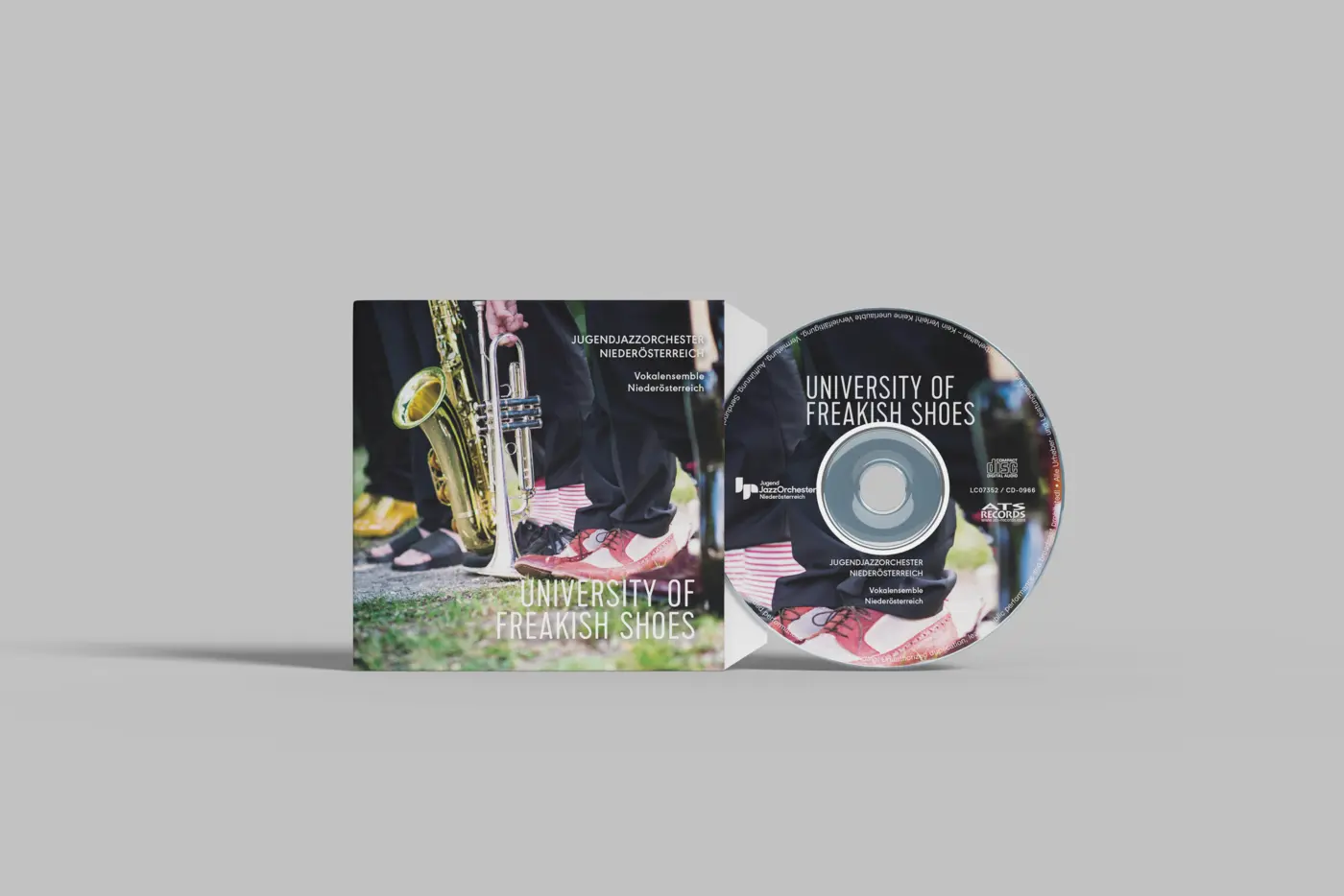 CD mit Hülle, auf der mehrere Beine unterhalb des Knies zu sehen sind. Zwei der Personen haben ihre Blechblasinstrumente am Boden abgestellt.