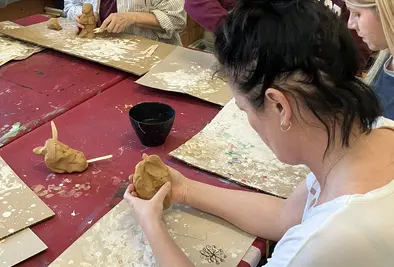 Vier Personen sitzen an einem Tisch und basteln individuell etwas mit Knetmasse.