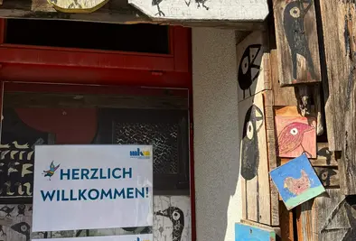 Eingang zum KUKUDU-Coaching mit vielen hölzernen KUKUDU Illustrationen um den Türrahmen.