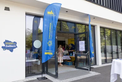 Eingangsbereich des Veranstaltungsortes mit Fahnen und einem Informationsaufsteller.