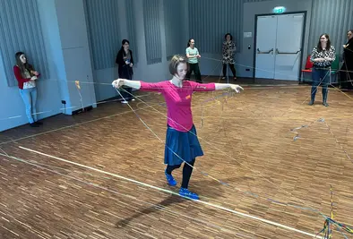 Person balanciert zwischen Personen und Wolle auf einer Linie am Boden.