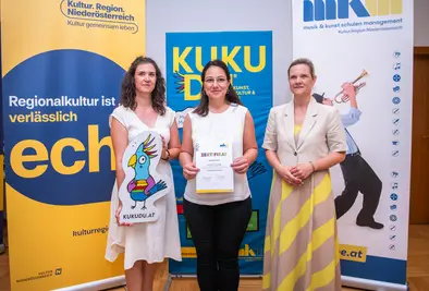 Teilnehmende Person und Vortragende posieren mit Zertifikat.