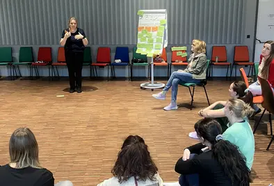 Teilnehmende sitzen im Raum und hören einem Vortrag zu.