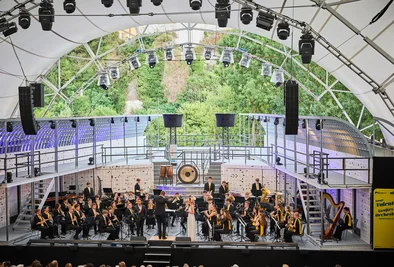 Orchester sitzt auf der Bühne in Melk, im Hintergrund Grün