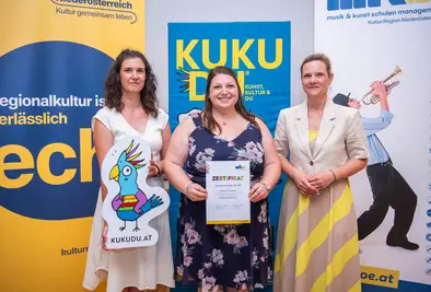 Teilnehmende Person und Vortragende posieren mit Zertifikat.