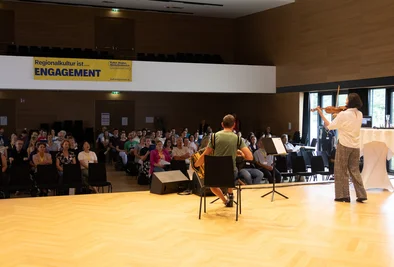 Musikerinnen und Musiker auf der Bühne während einer Präsentation.
