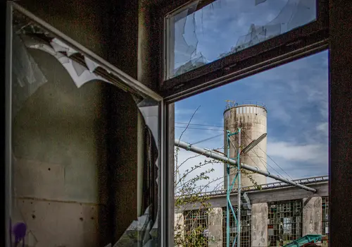 Zerbrochenes geöffnetes Fenster in einer verlassenen Industrieanlage.